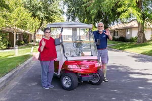 couple stand by gold cart and waves 