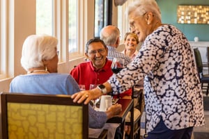 Woman standing next to dining table with two people