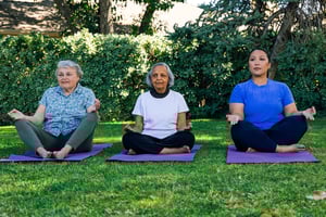 Three women do yoga on the grass