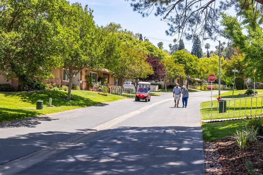 couple and golf cart coming down a street