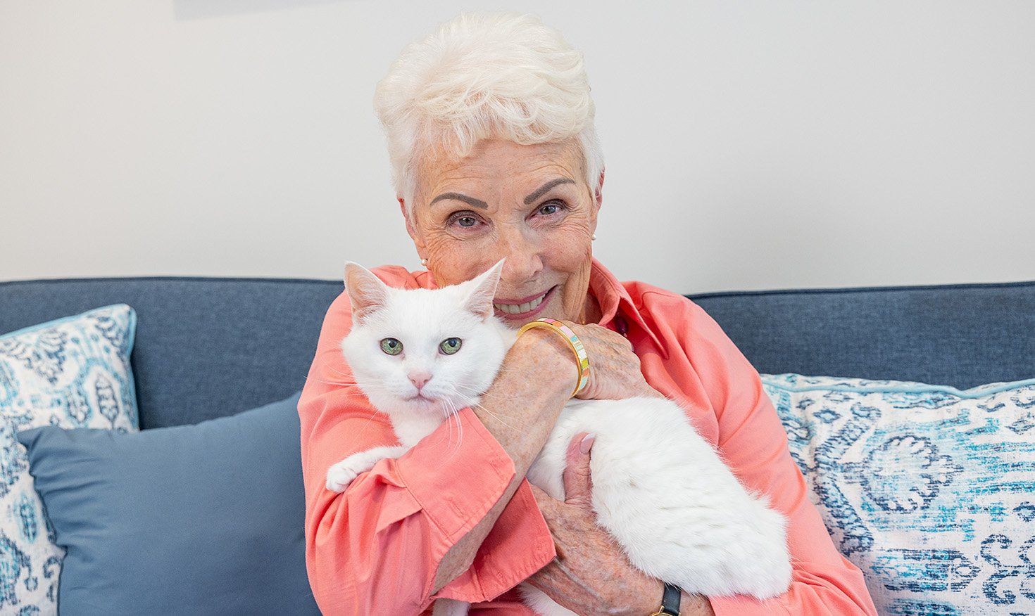 senior holding her white cat close while smiling