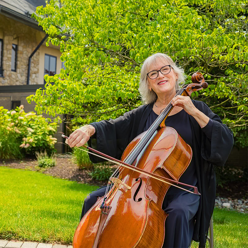 senior playing the cello outside