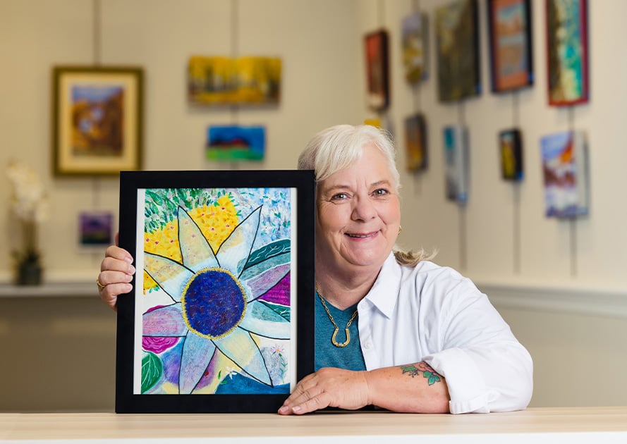 senior posing with their art at an art show