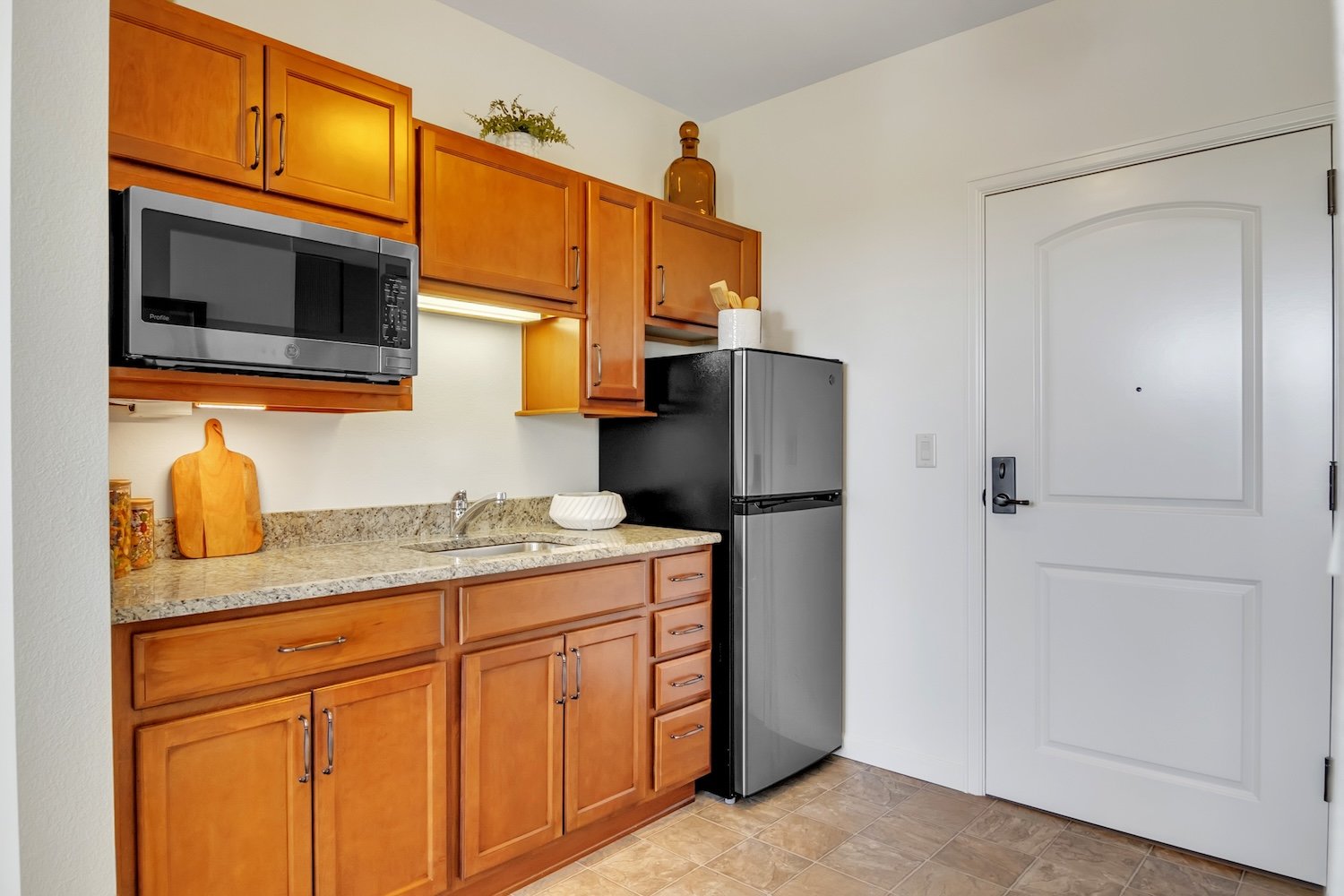 Kitche with brown cabinets, a microwave, and refrigerator