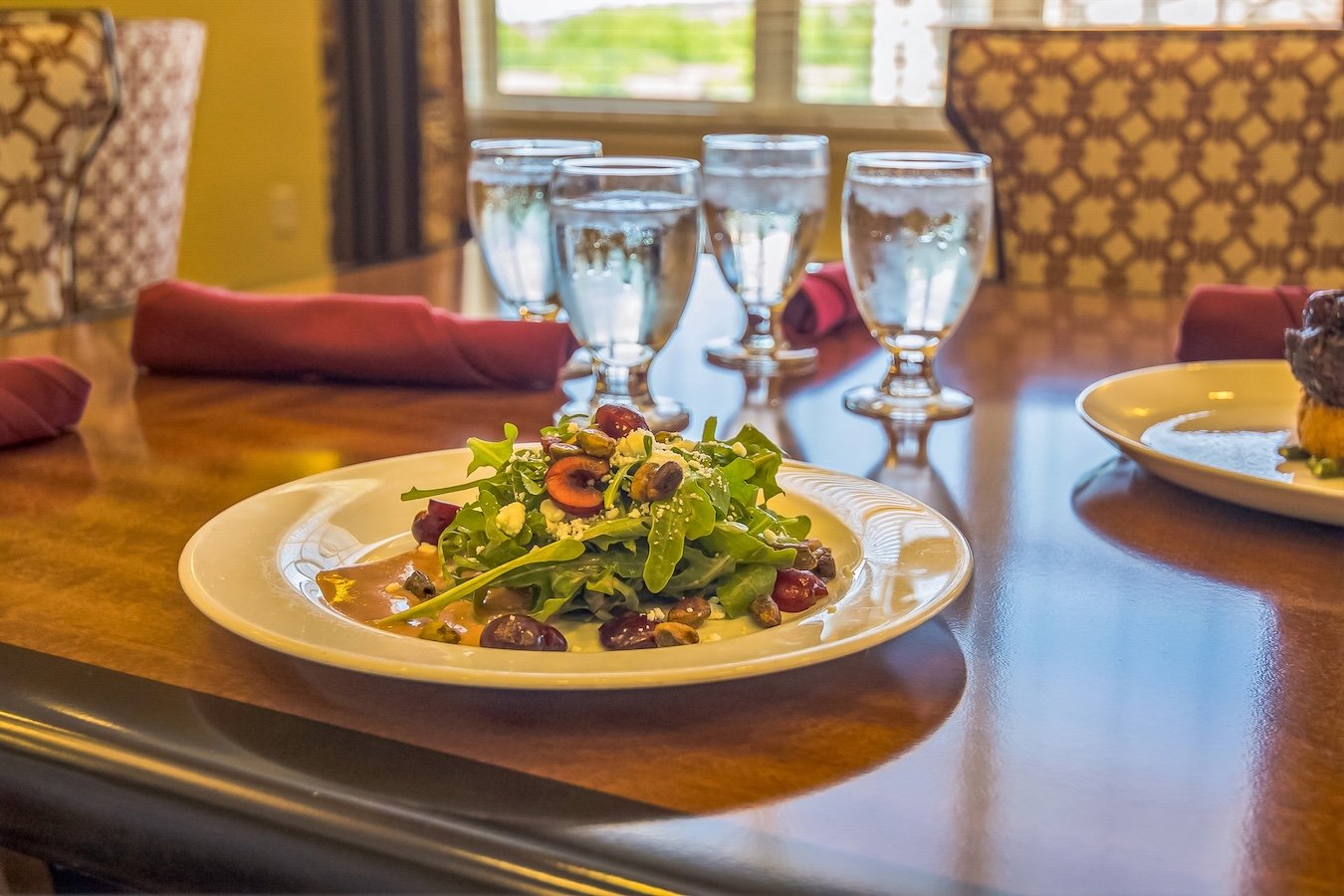 dinner place setting with a plated salad and four water glasses
