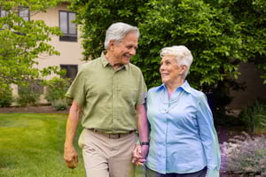 senior couple holding hands outside while smiling at each other