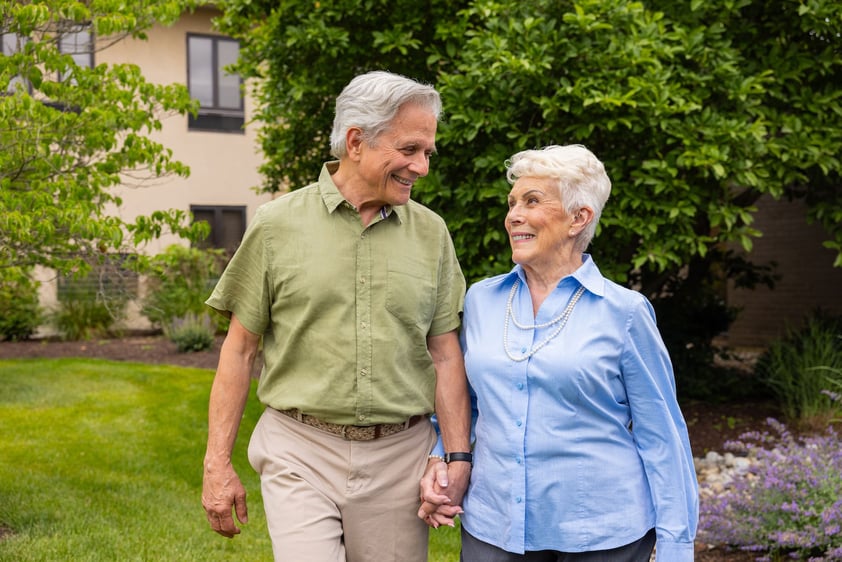 senior couple holding hands outside while smiling at each other