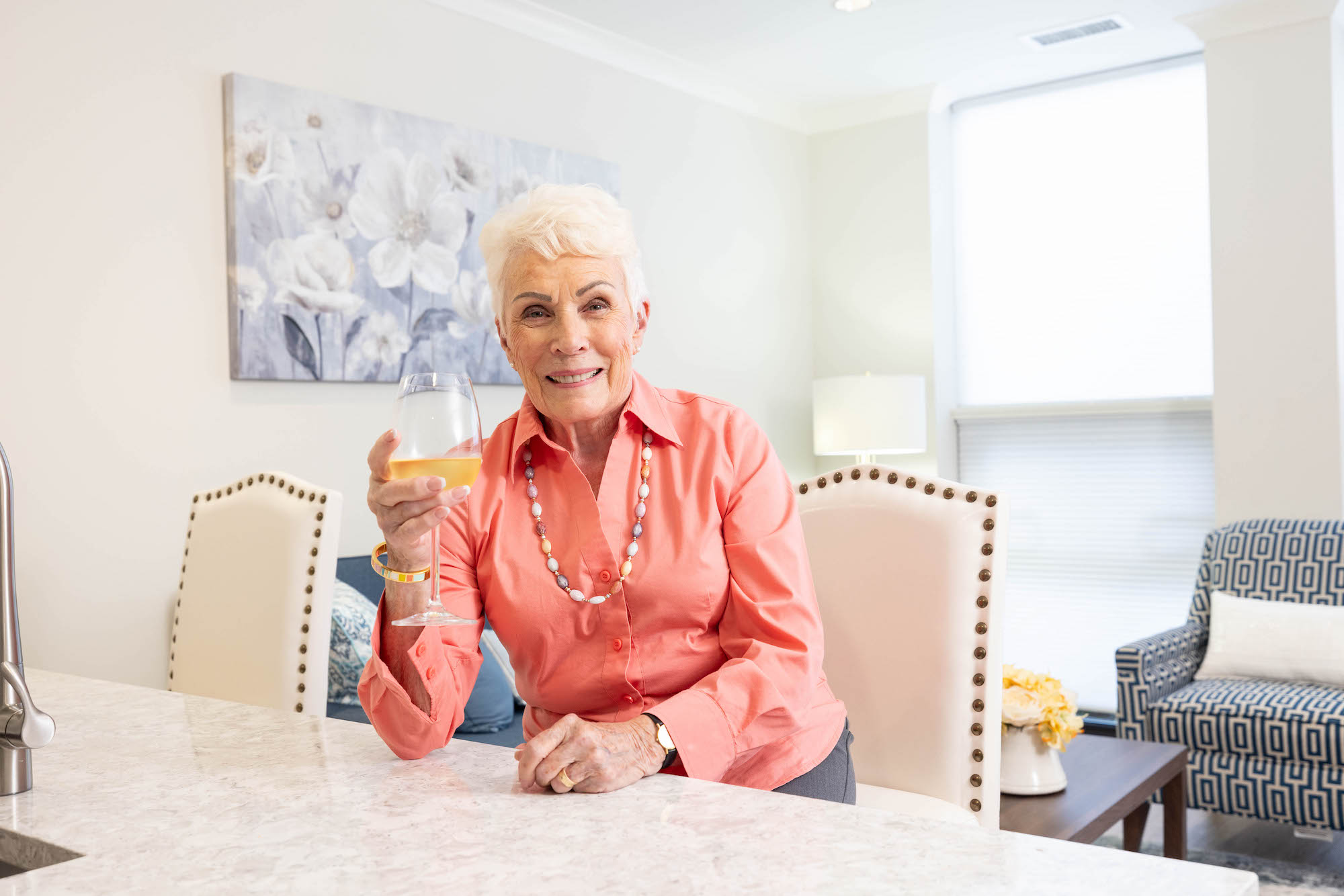 senior resident enjoying wine in apartment kitchen